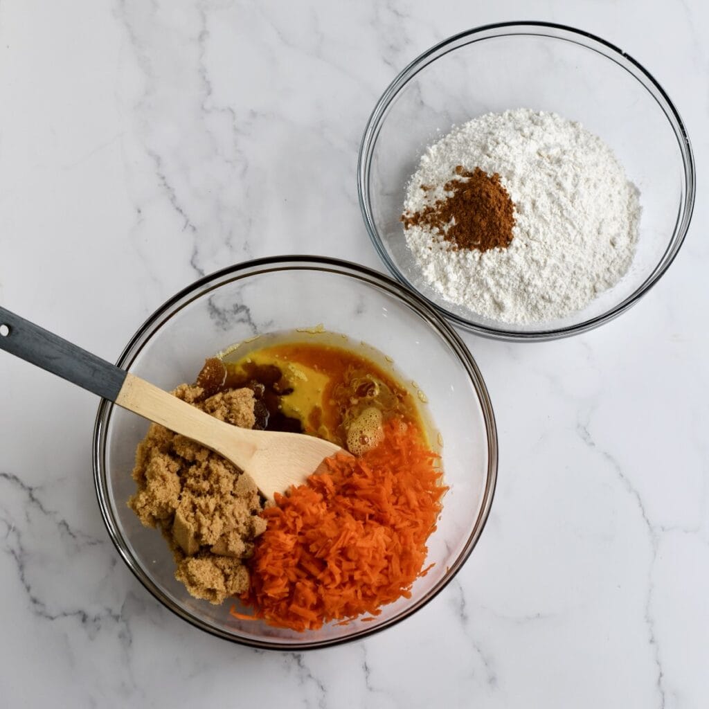 A glass bowl with wet ingredients for carrot bundt cake. A second glass bowl with dry ingredients for carrot bundt cake.