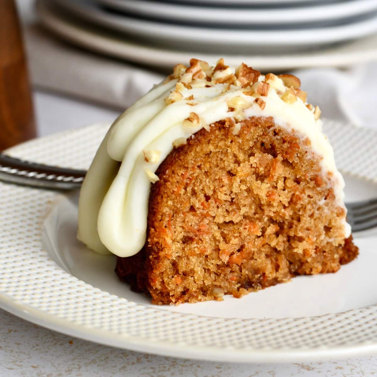 A slice of carrot bundt cake on a white plate with a fork.