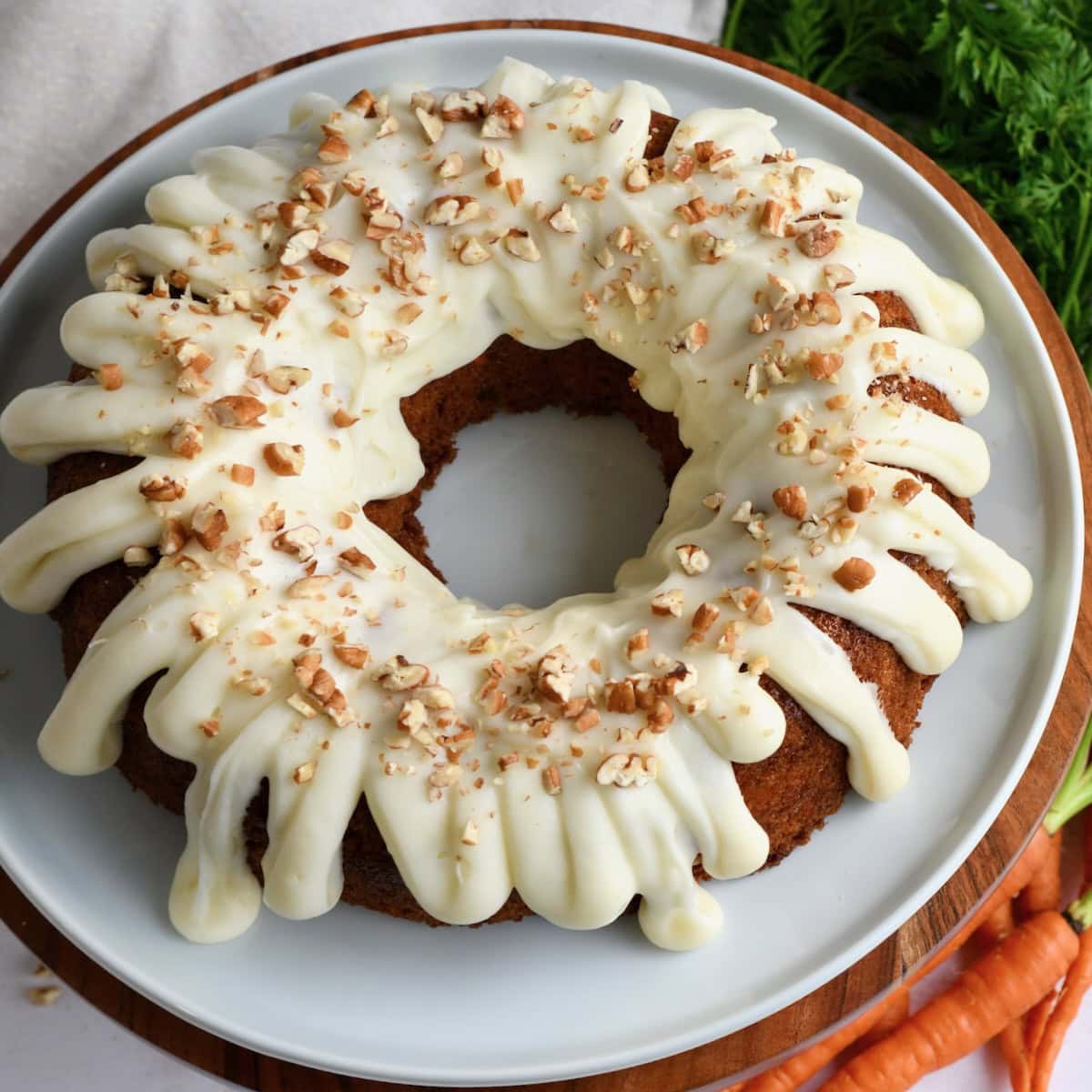 Overhead image of carrot bundt cake on a white plate on a wooden cake stand.