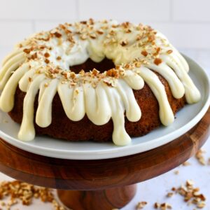 A carrot bundt cake on a wood cake pedestal.