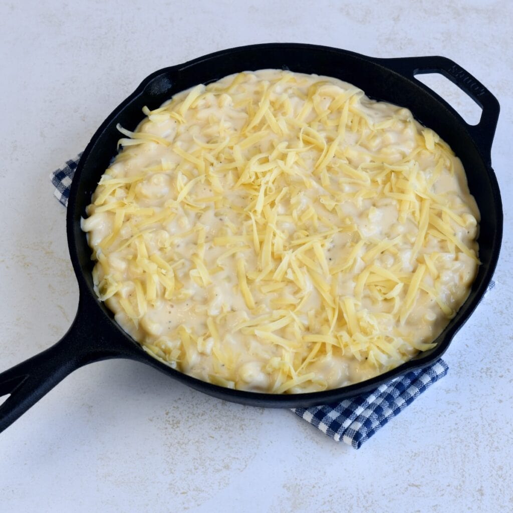 A cast iron skillet with gouda mac and cheese on a plaid linen.