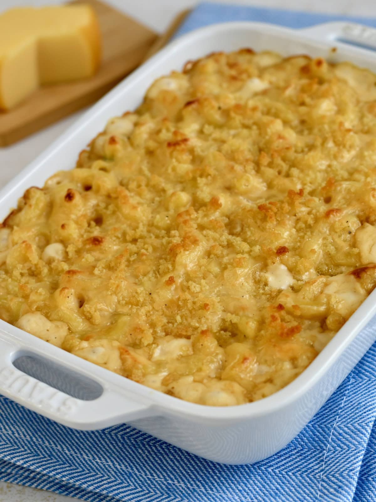 A white baking dish with baked gouda mac and cheese on a blue linen.