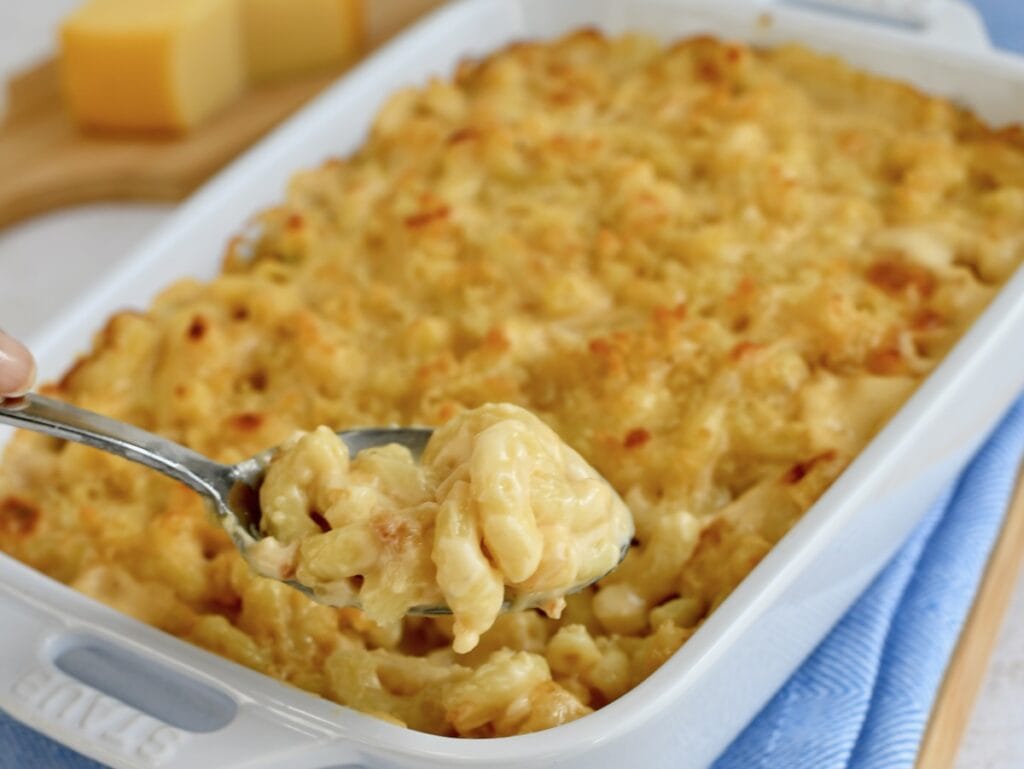 A white baking dish with gouda mac and cheese on a spoon.
