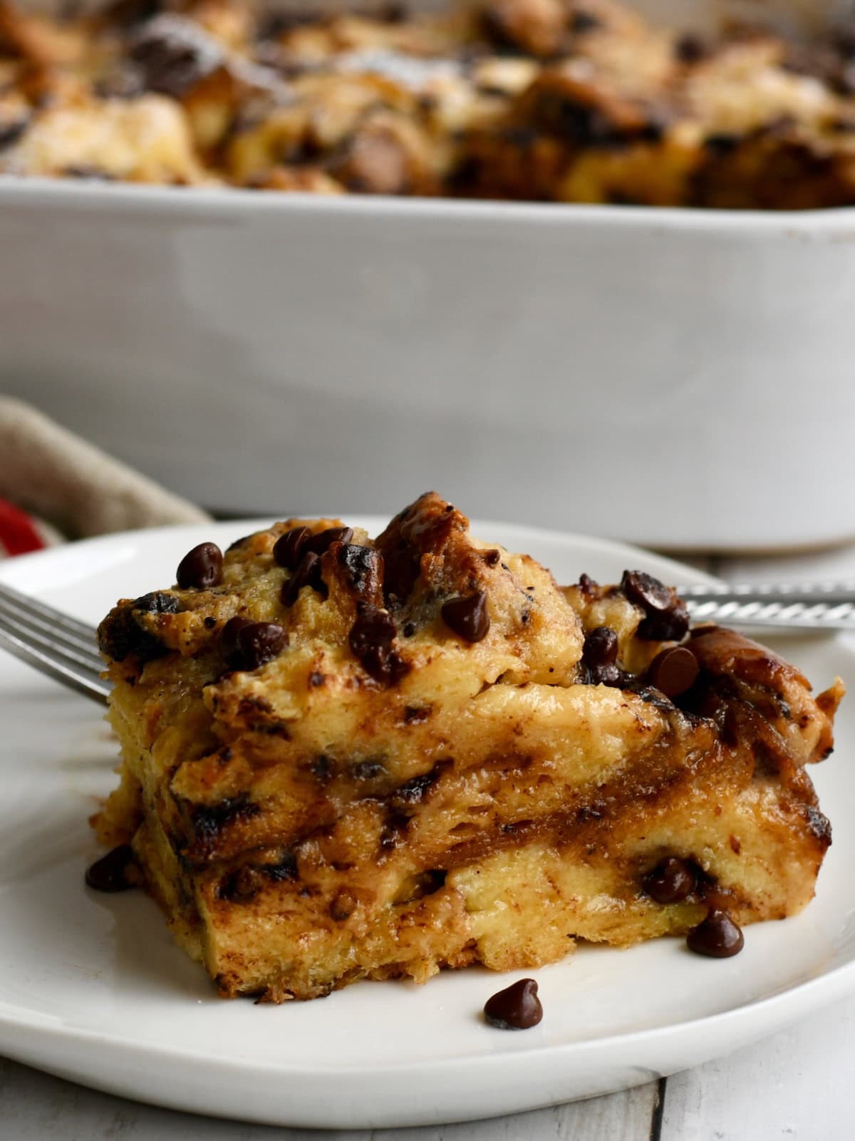 Portion of panettone bread pudding on a white plate with a fork.