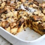 White baking dish of panettone bread pudding with a portion missing.