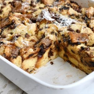 White baking dish of panettone bread pudding with a portion missing.