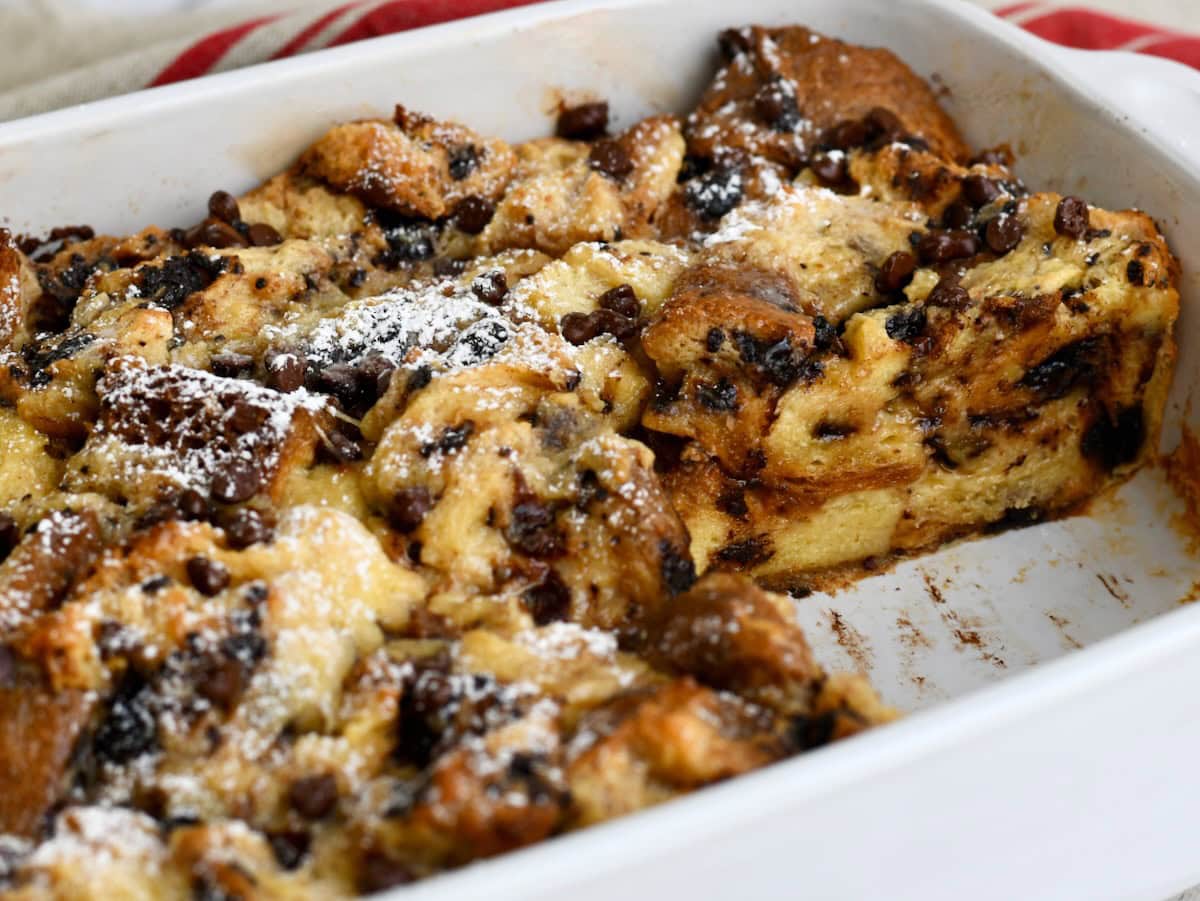 Panettone bread pudding in a white baking dish with one portion missing.