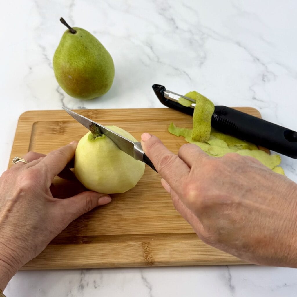 Peeling and slicing pears on a wooden background.