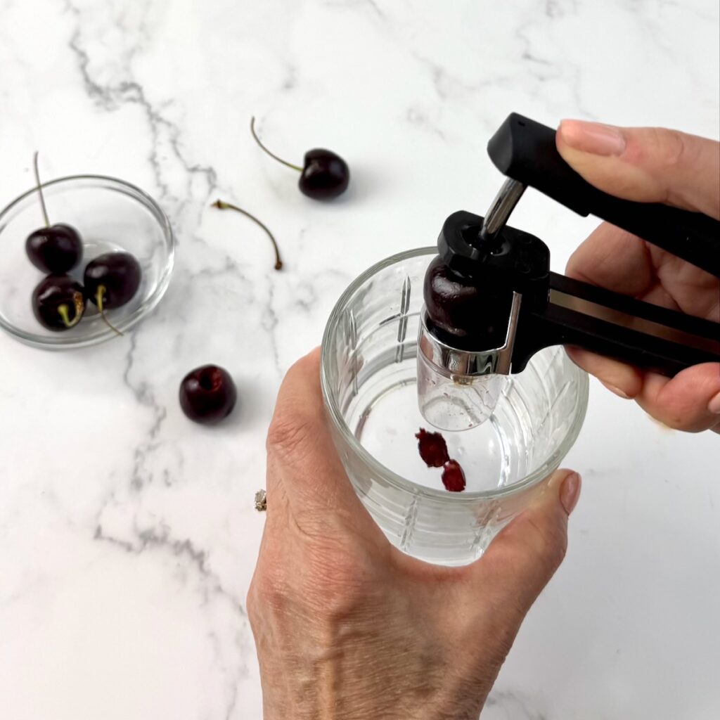 Using a cherry pitter to pit fresh cherries.
