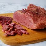 Corned beef shredded on a wooden cutting board.