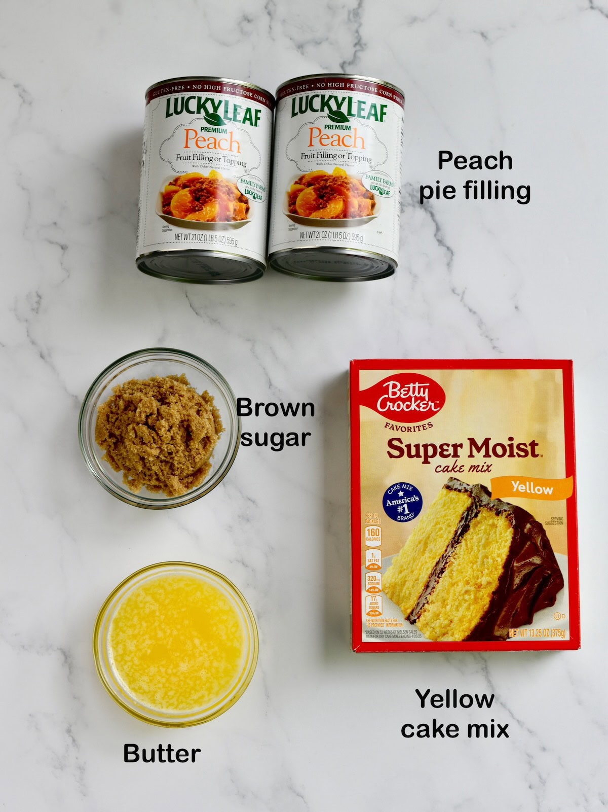 Ingredients for cake mix peach cobbler. L-->R: peach pie filling, brown sugar, butter, and yellow cake mix.