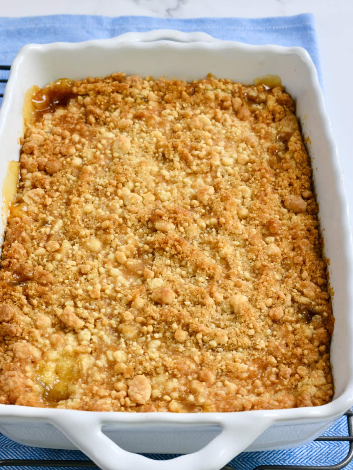Baked cake mix peach cobbler in a white baking dish.