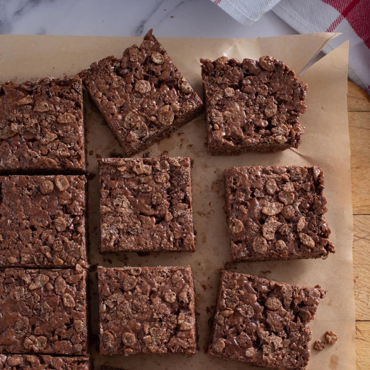 Close up of chocolate rice krispie squares on a piece of parchment.