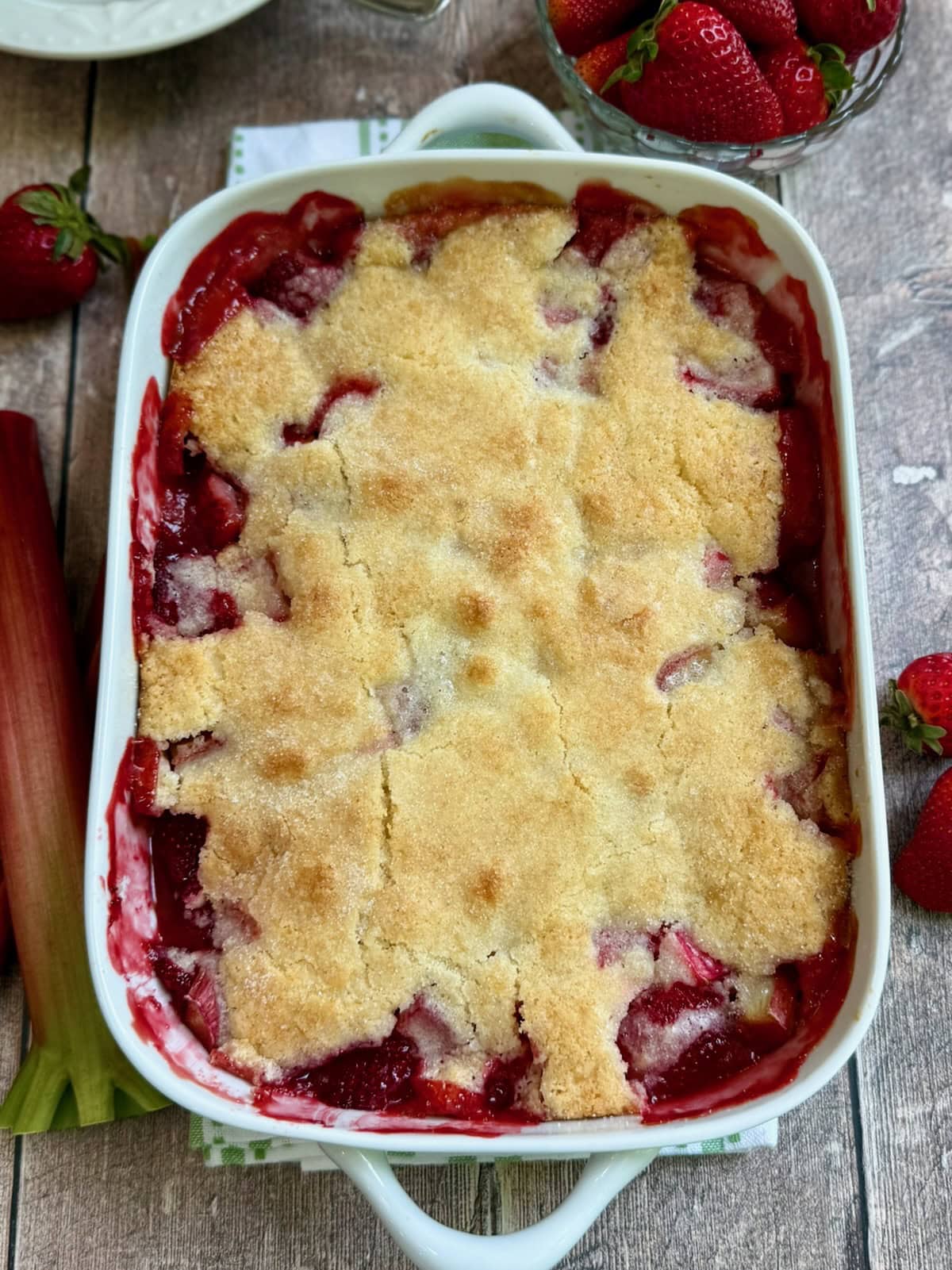 Baked strawberry rhubarb cobbler in a white baking dish.