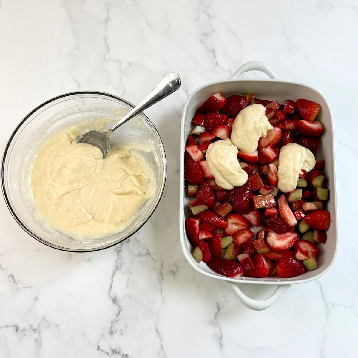 Cobbler dough in a bowl next to fresh fruits in a baking dish.