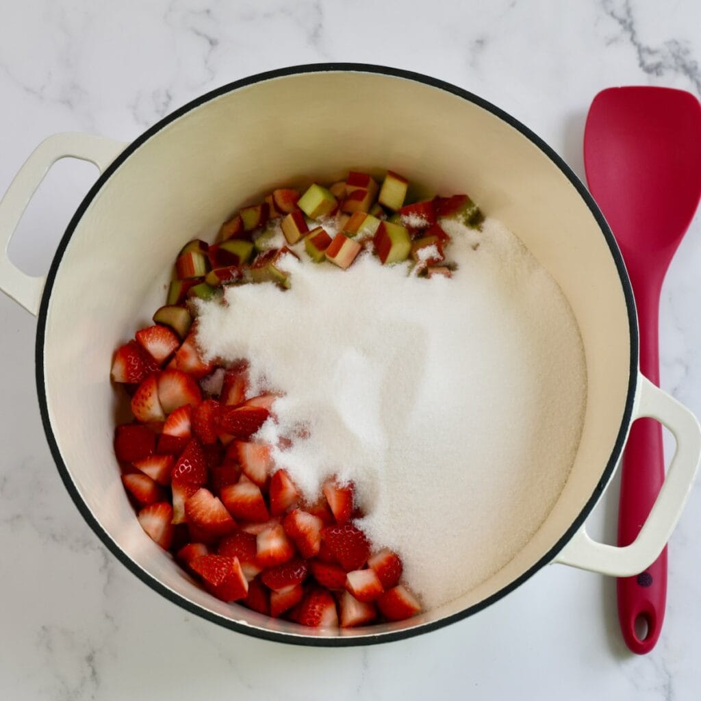 Sliced strawberries, rhubarb, and sugar in a large pot.