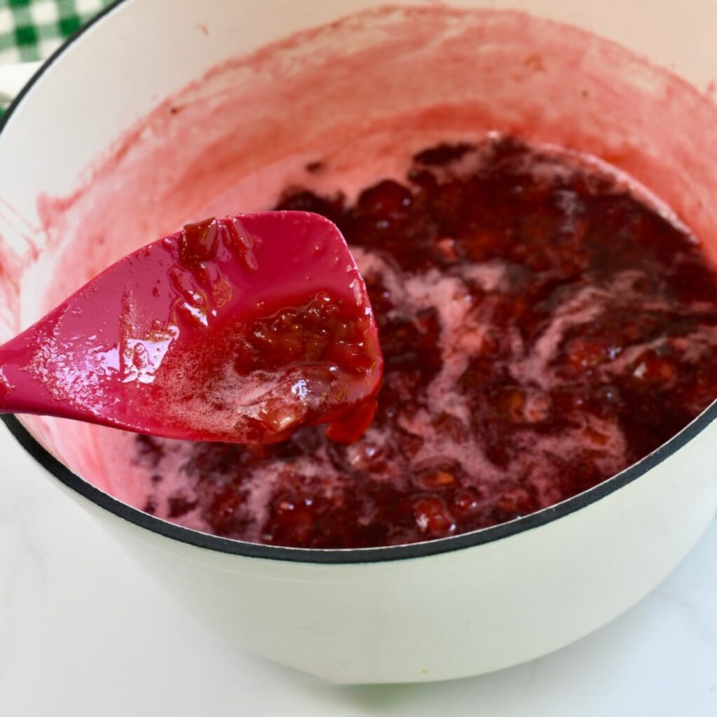 Rubber spatula scooping up some strawberry rhubarb mixture once it has been cooked down.