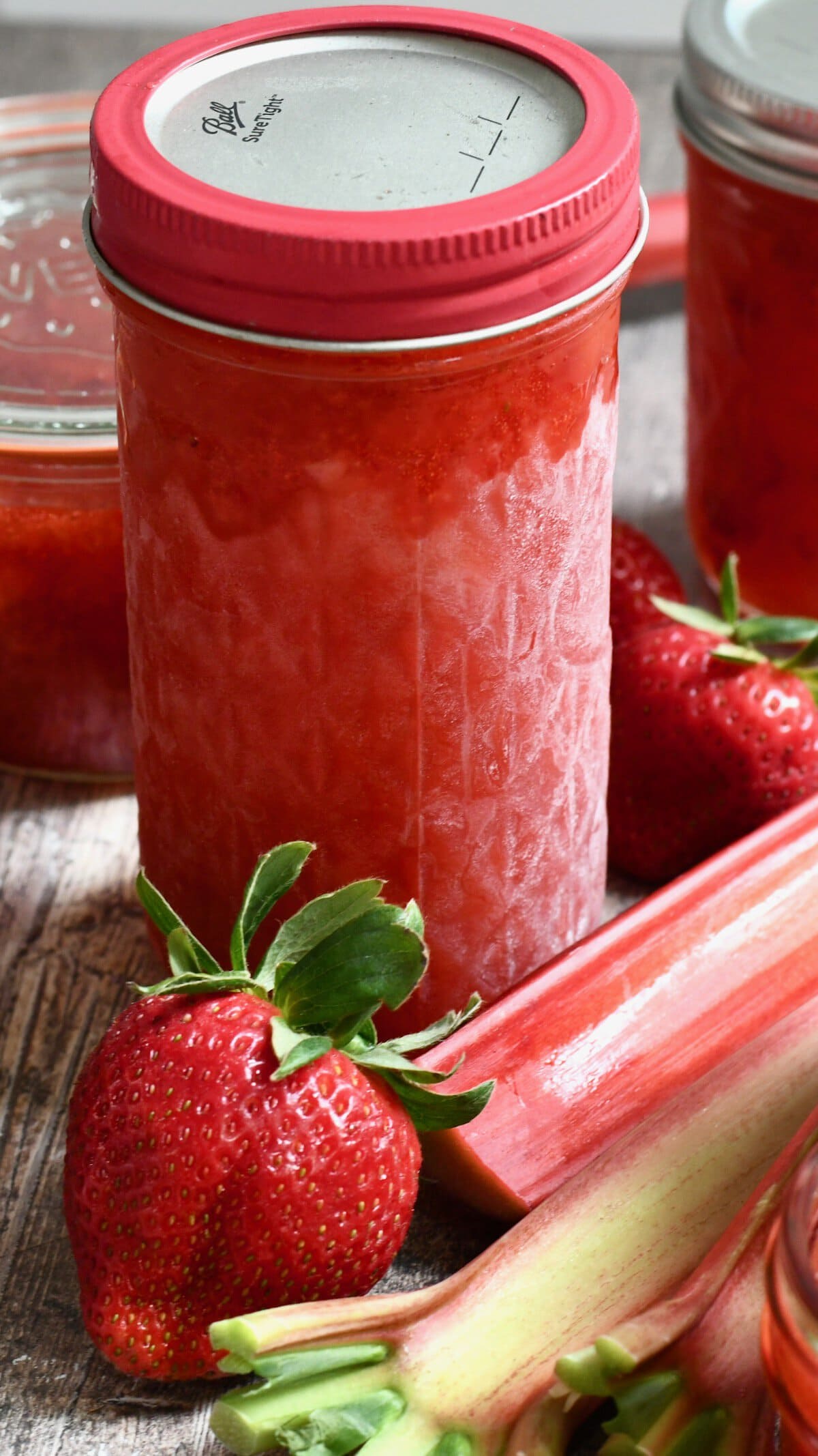 Large glass jar of frozen strawberry rhubarb freezer jam.