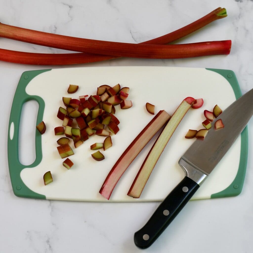 Chopping fresh rhubarb on a cutting board.
