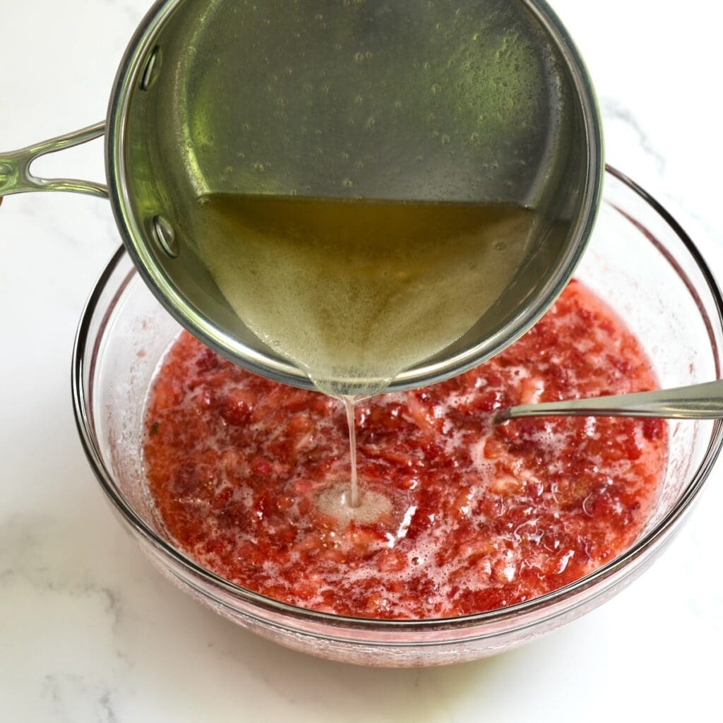 Pouring the melted pectin into the prepared strawberry rhubarb mixure.