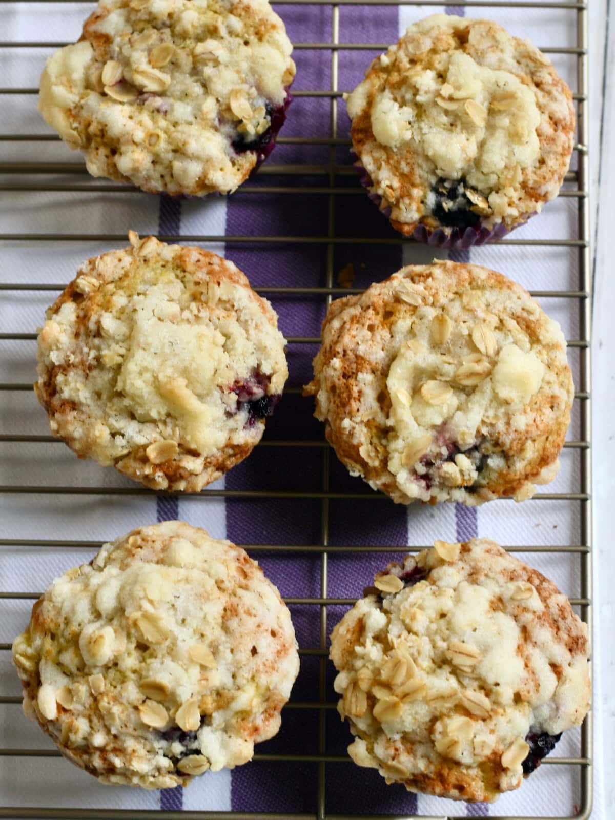 Overhead shot of six banana blackberry muffins on a wire rack.