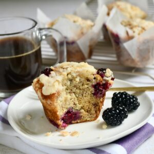 Side view of a banana blackberry muffin with a bite taken out of it.