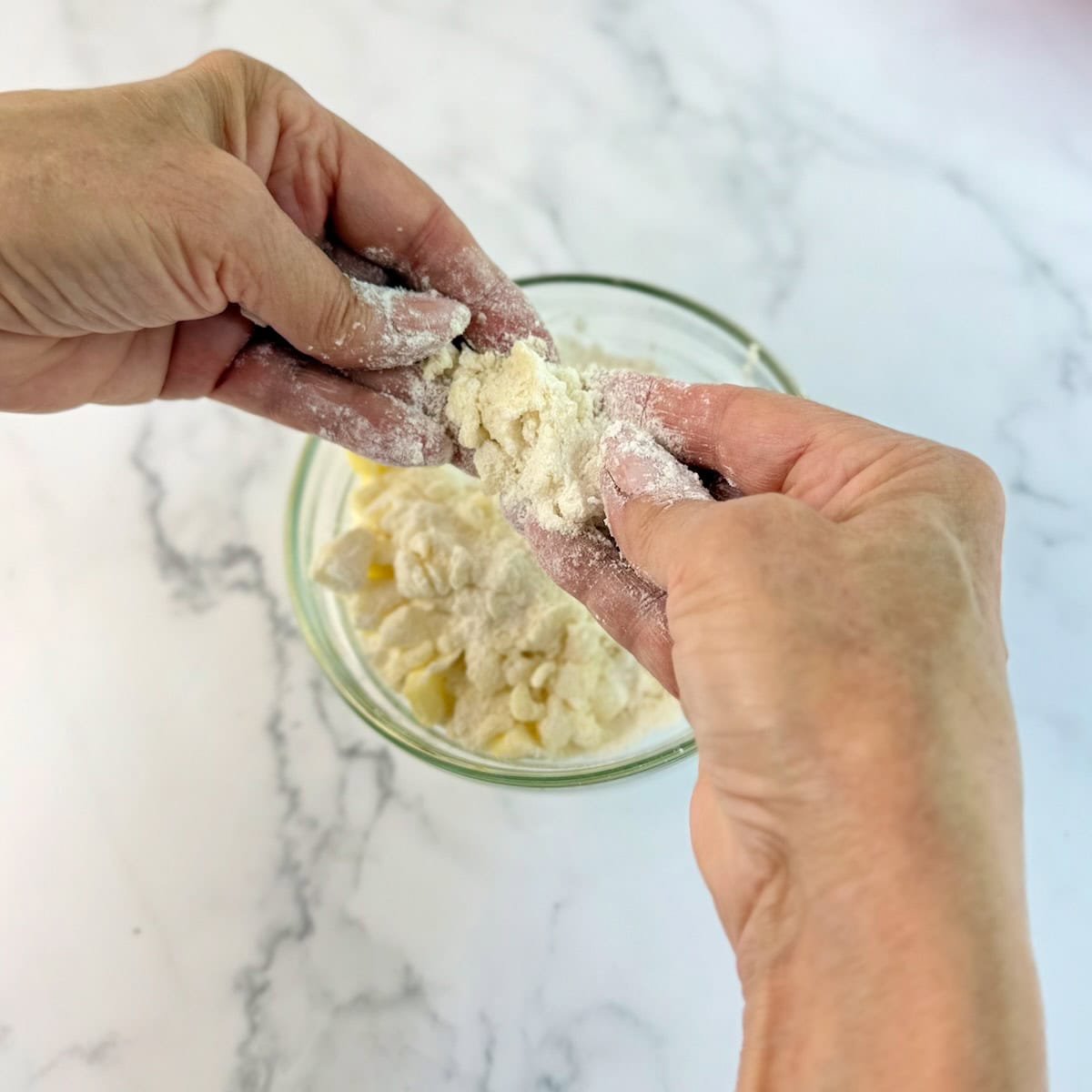 Hands breaking up the butter for the streusel topping.