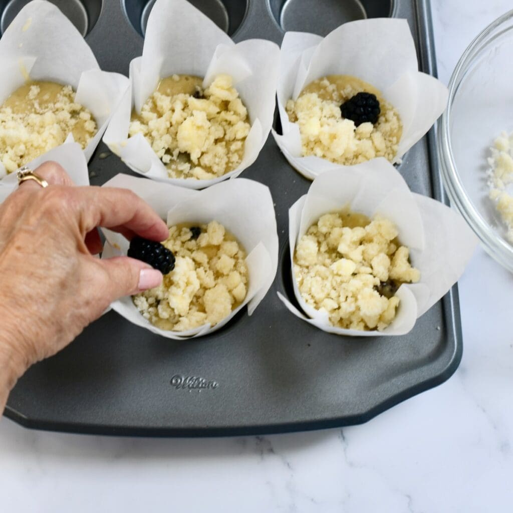 Adding fresh blackberries on top of the banana blackberry muffin batter.