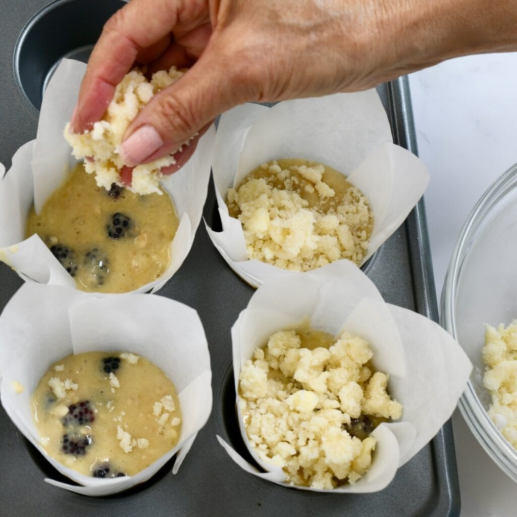Sprinkling streusel on top of muffin batter before baking.