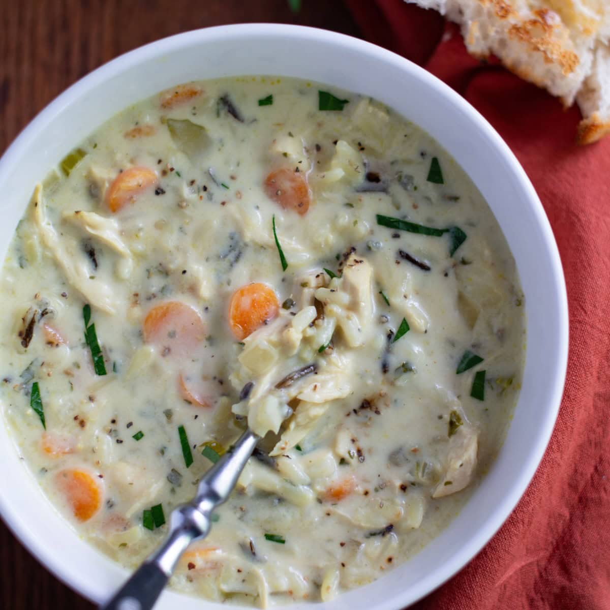 Bowl of chicken wild rice soup with a spoon in it.
