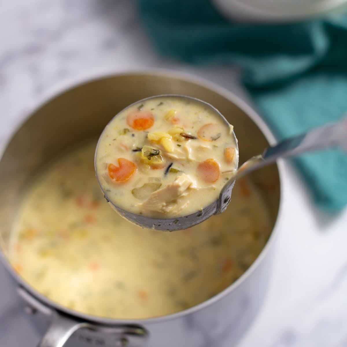 Large ladle of chicken wild rice soup being scooped up from a pot.
