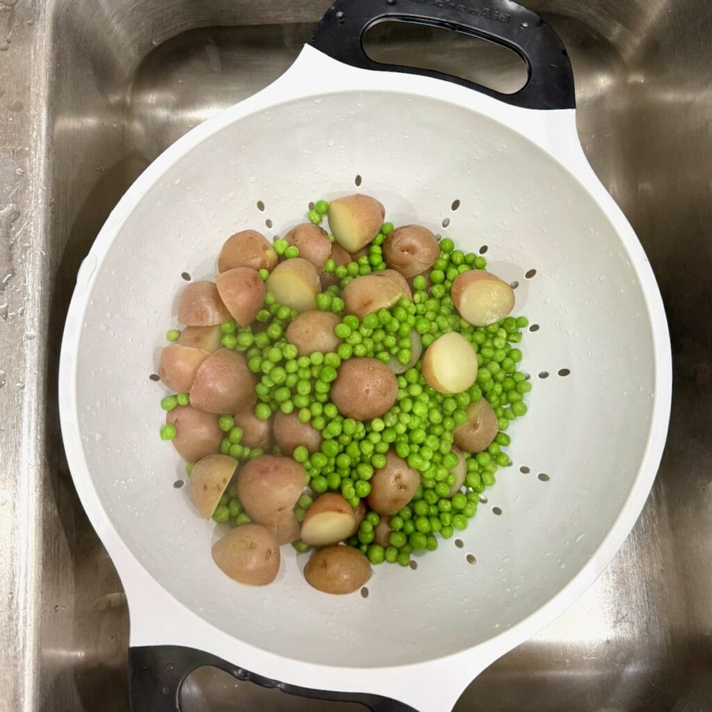 Cooked potatoes and peas in a colander.