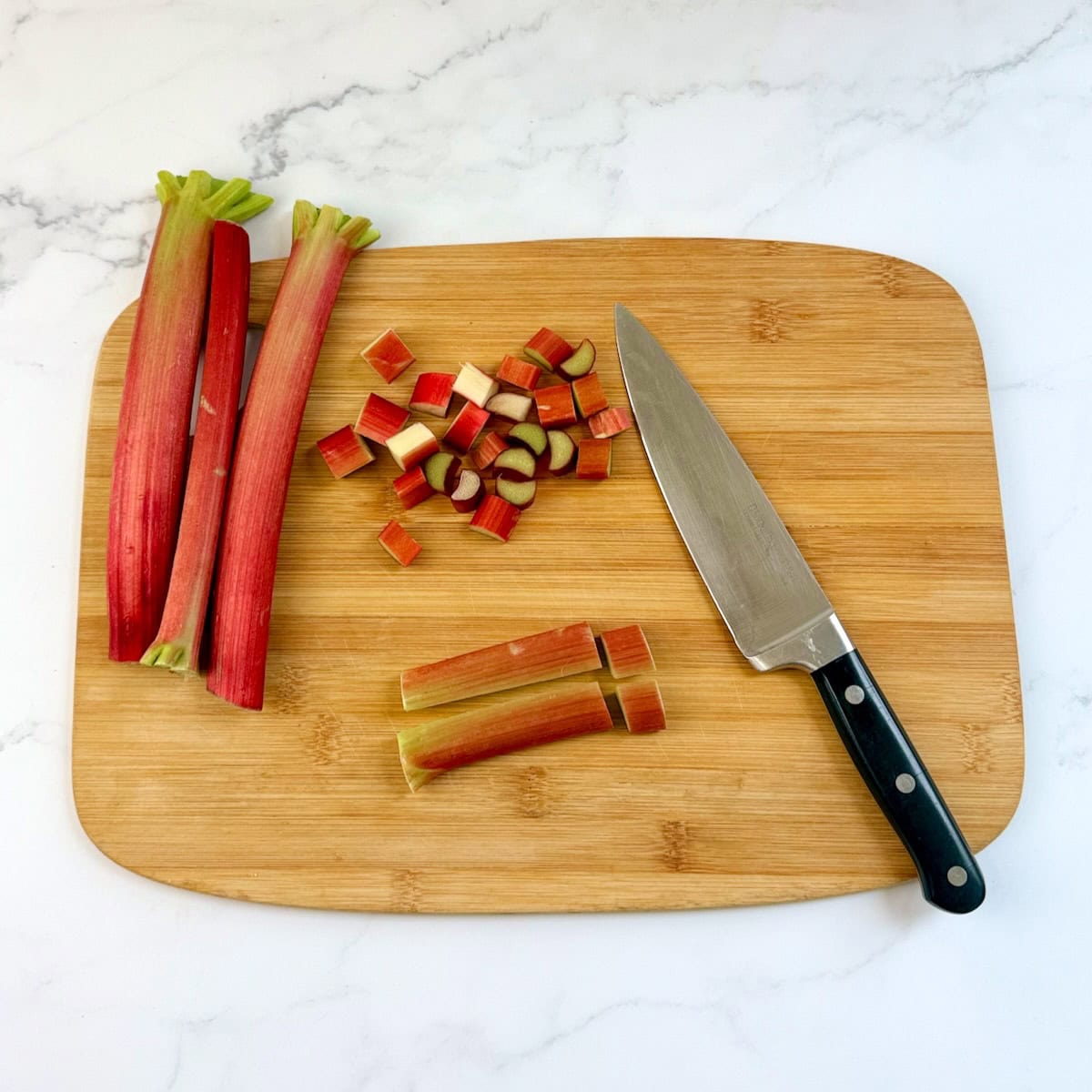 Dicing rhubarb on a cutting board.