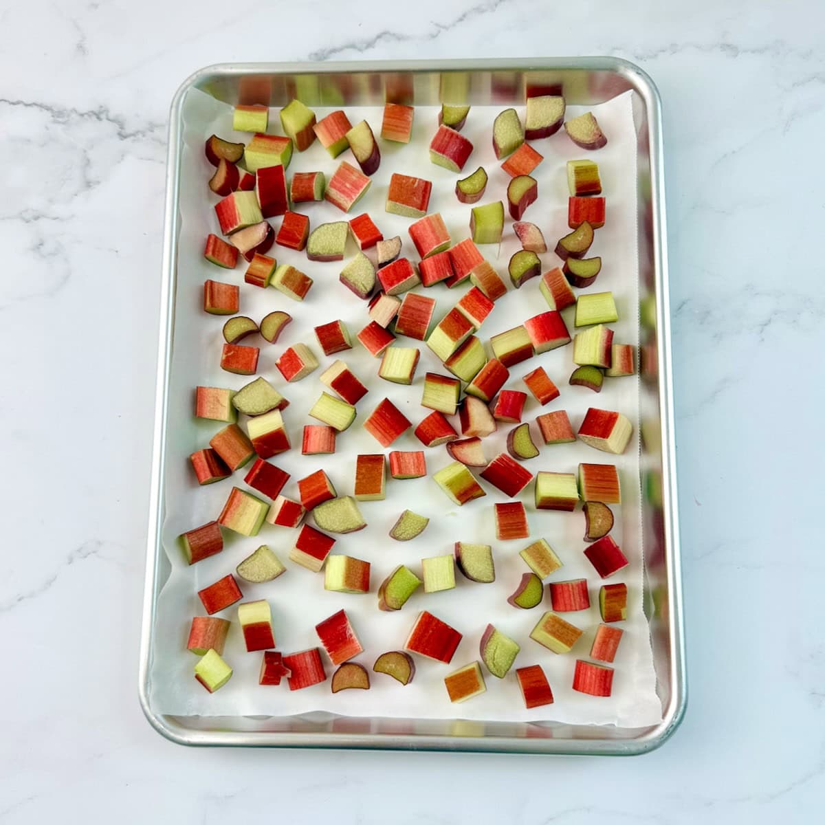 Freshly diced rhubarb on a sheet pan to freeze.