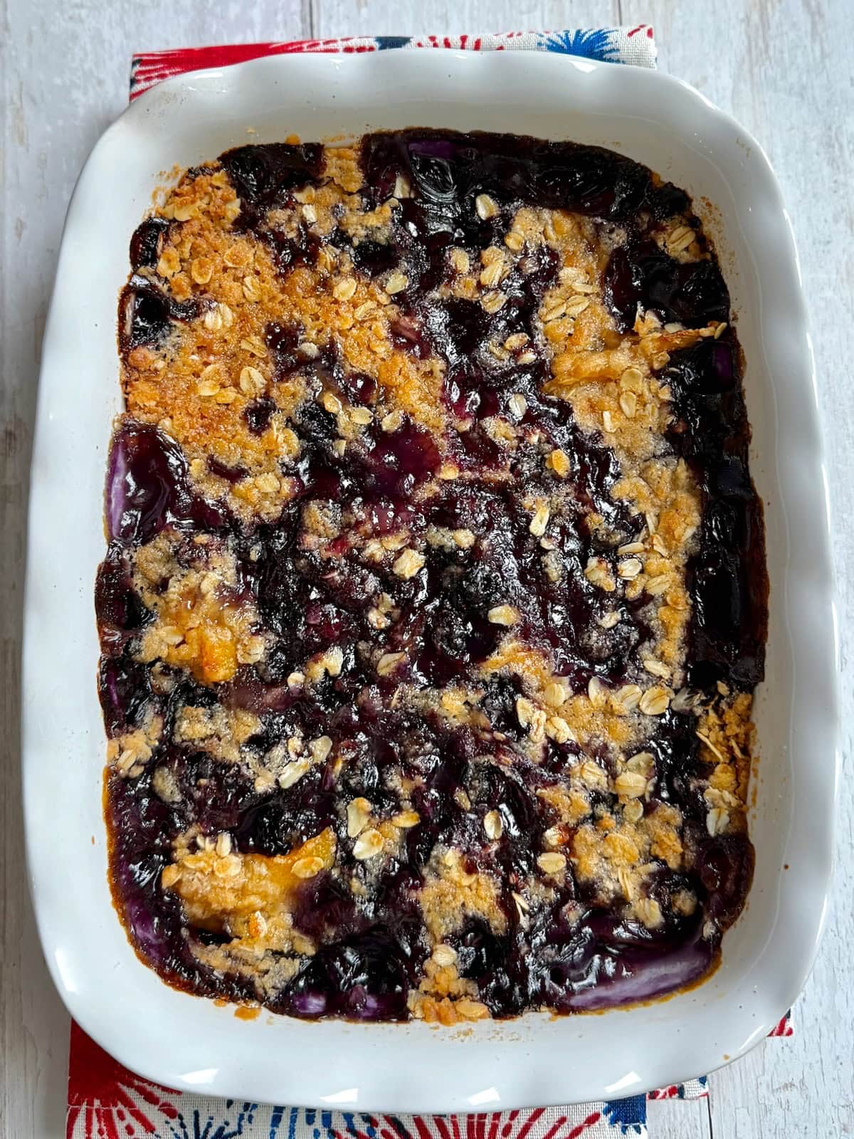 Overhead shot of a baked peach blueberry cobbler in a white baking dish.