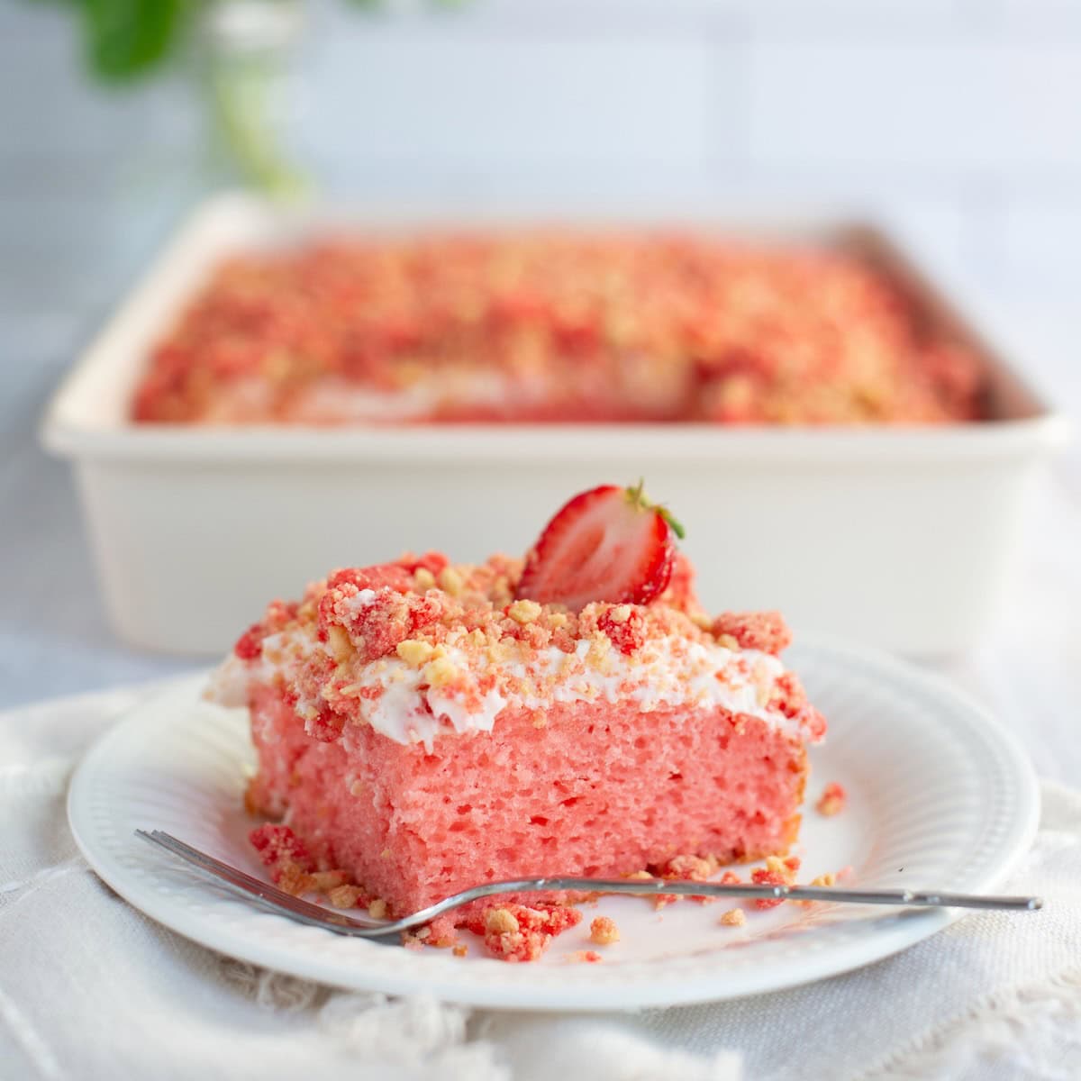 Side view of strawberry crunch cake on a plate with a fork.