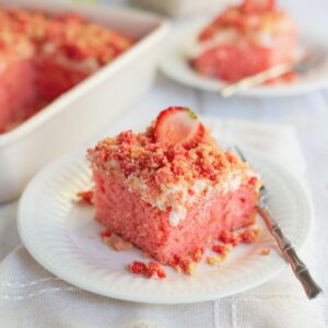Slice of strawberry crunch cake on a plate with a fork.
