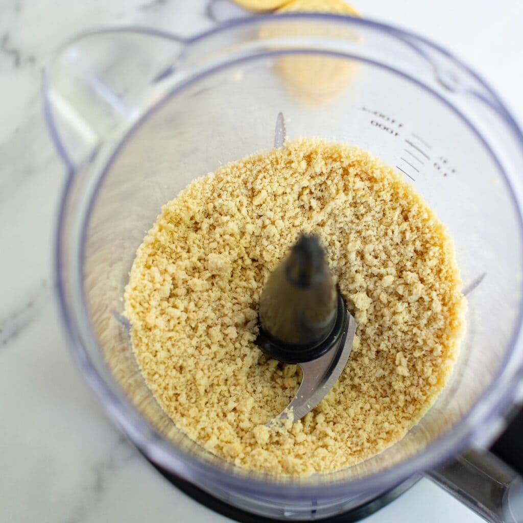 Golden Oreo cookies crushed into crumbs in a food processor.