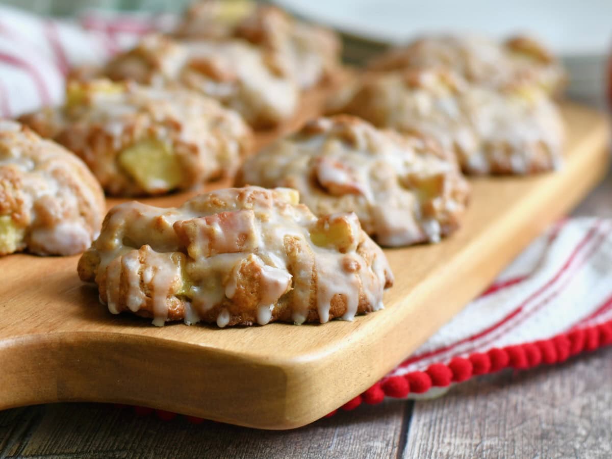 Side view of baked applesauce fritters lined up on a wooden board.