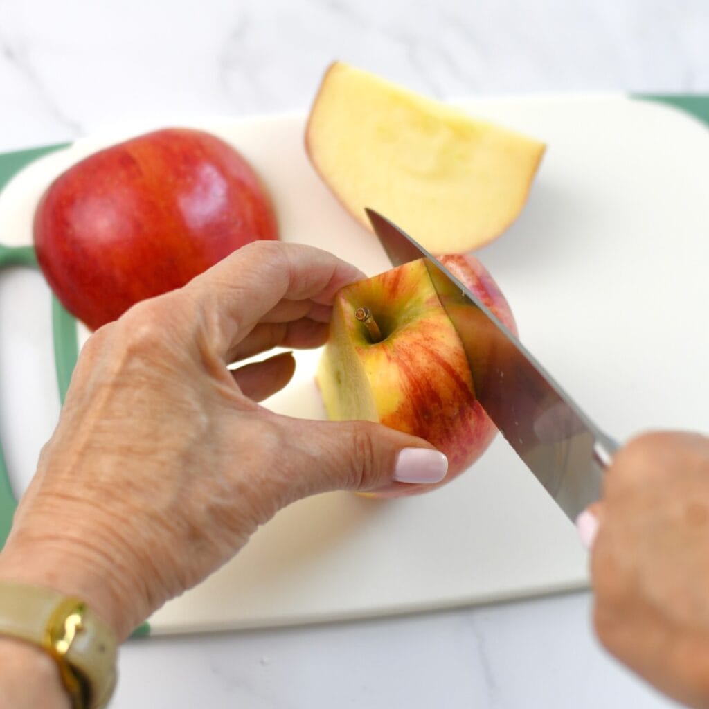 Using a chef's knife to slice an apple on a cutting board.