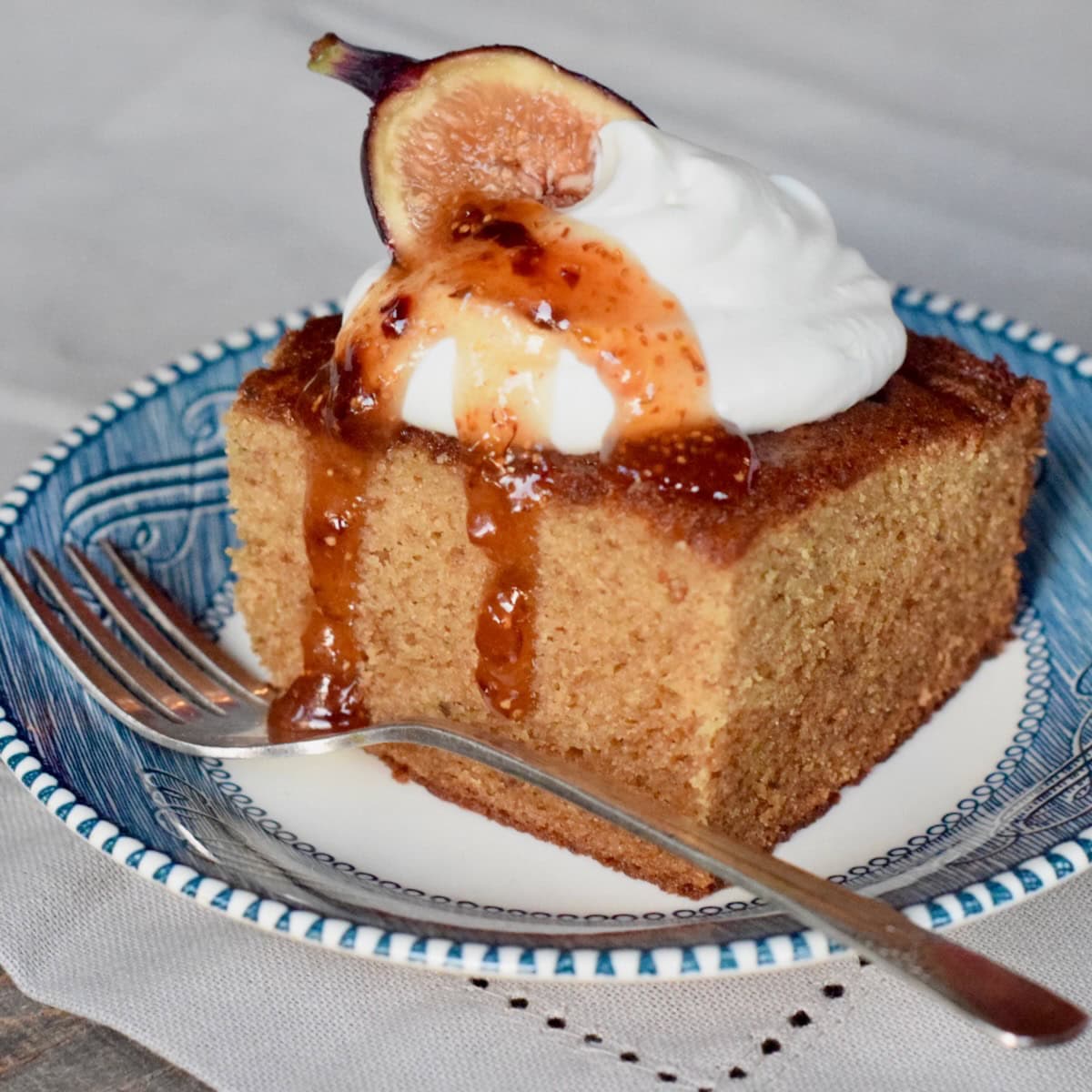 Slice of fig cake with whipped topping on top.