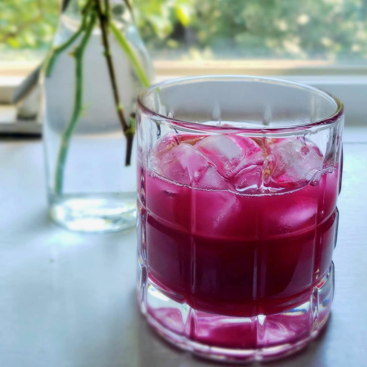 Side view of a glass of muscadine juice with ice.