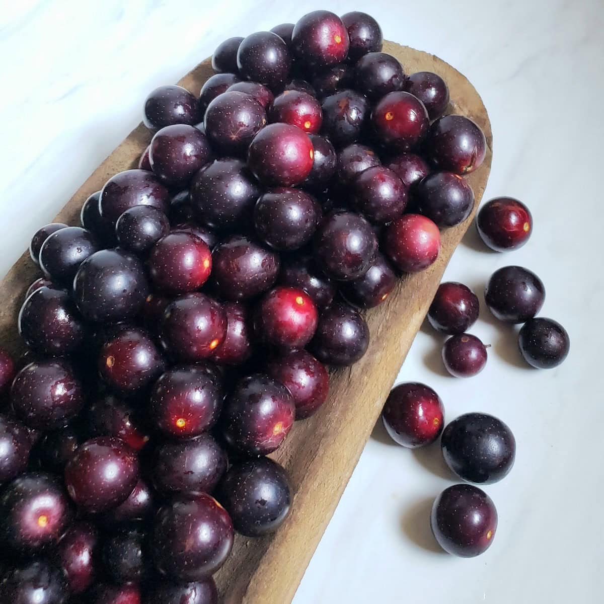 Muscadine grapes in a large wooden bowl.