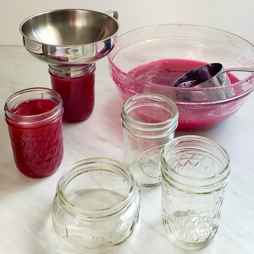 Placing muscadine jelly into jars.