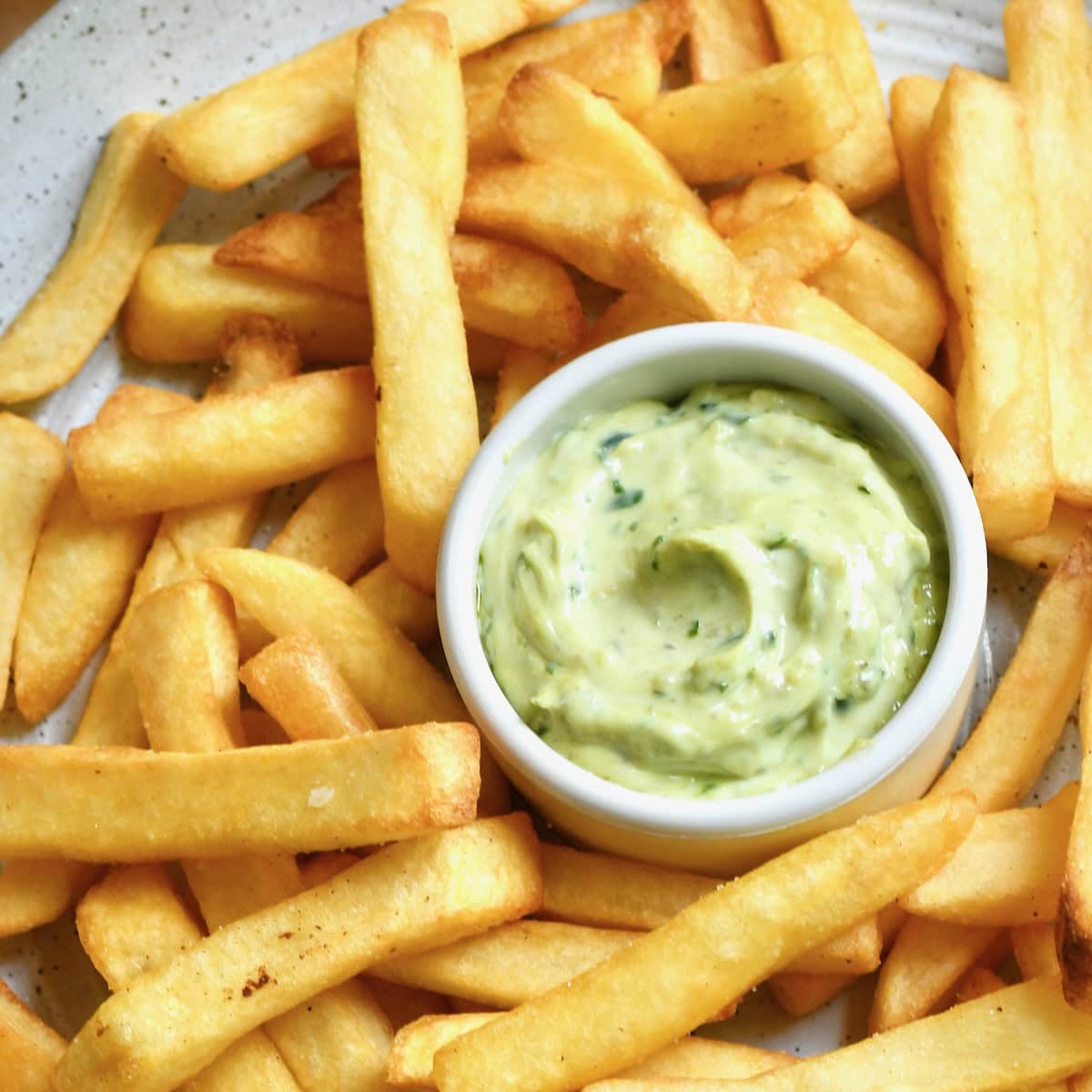 Pesto mayo served with fries on a plate.