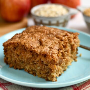 Side view of a slice of apple oatmeal cake on a blue plate.