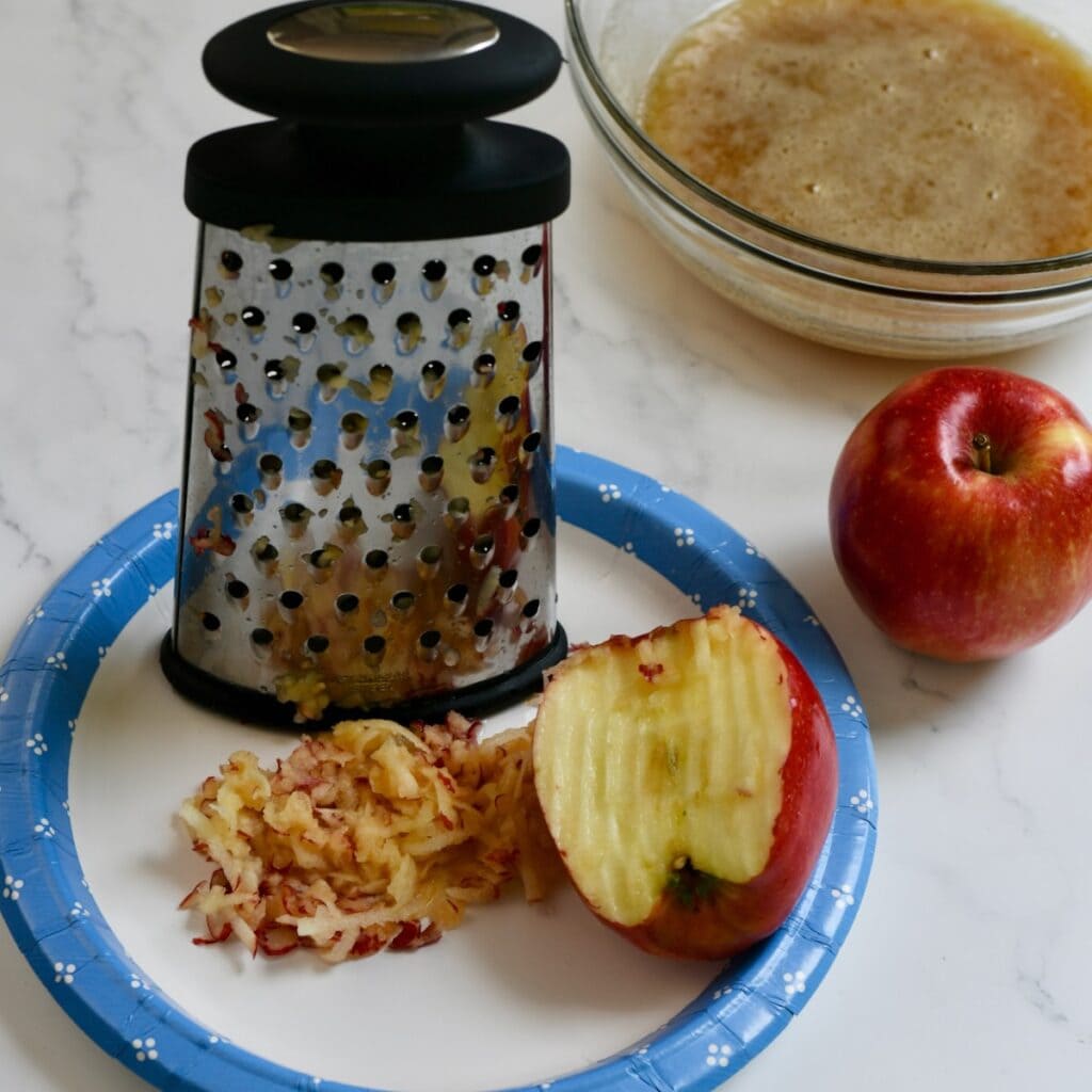 Using a box grater to grate an apple.