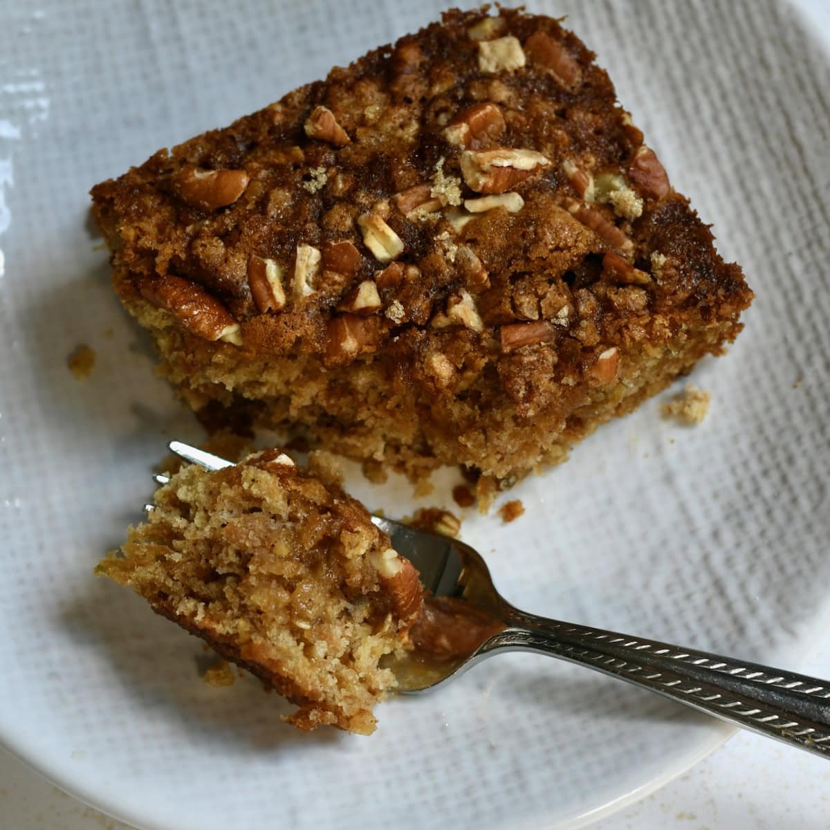 Apple oatmeal cake on a plate with a fork taking a bite.