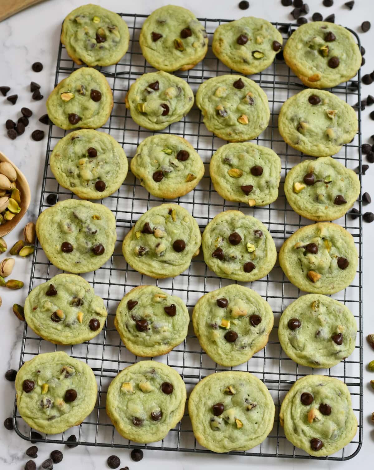 Overhead shot of chocolate chip pistachio cookies on a wire rack.