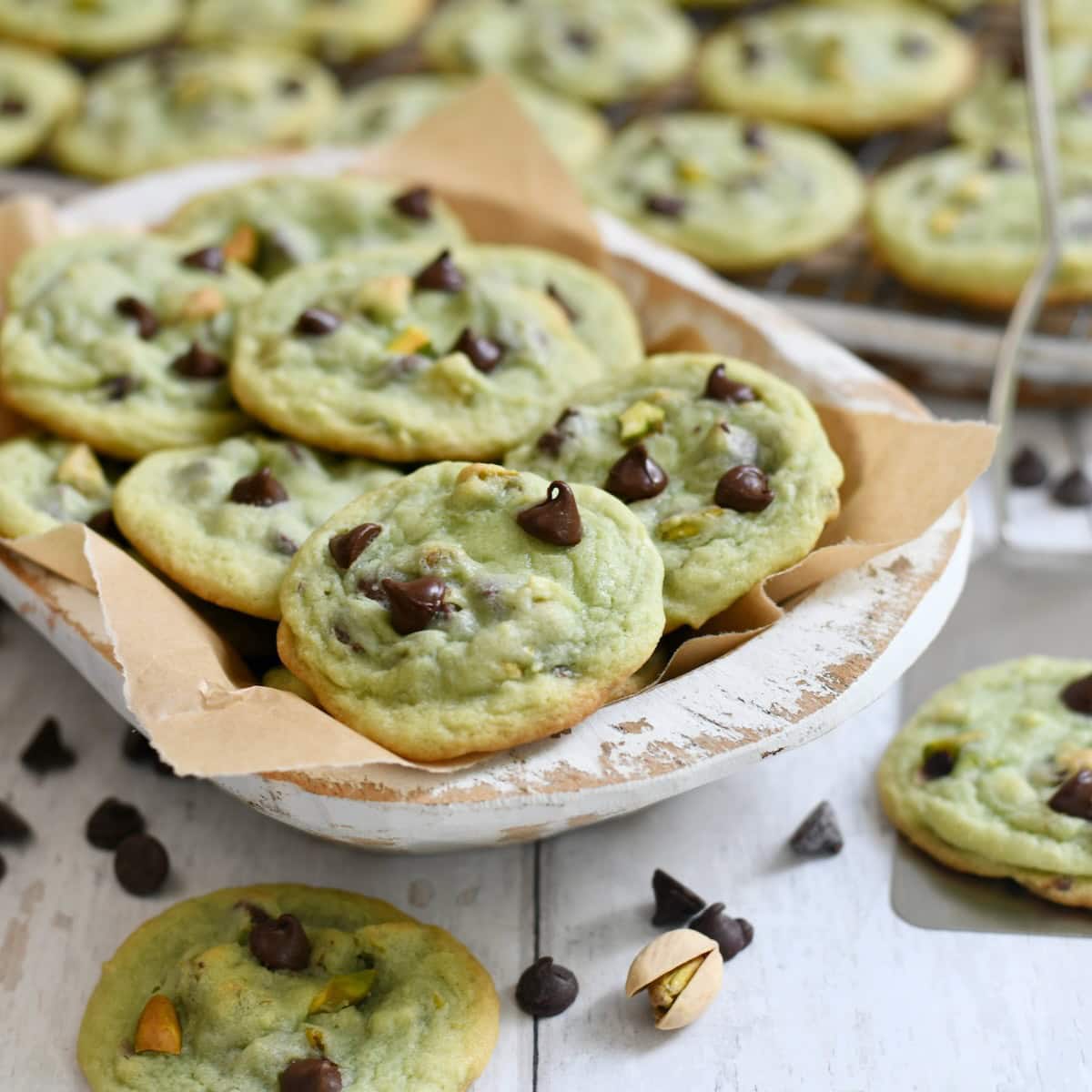 Chocolate chip pistachio cookies served on a platter lined with parchment paper.